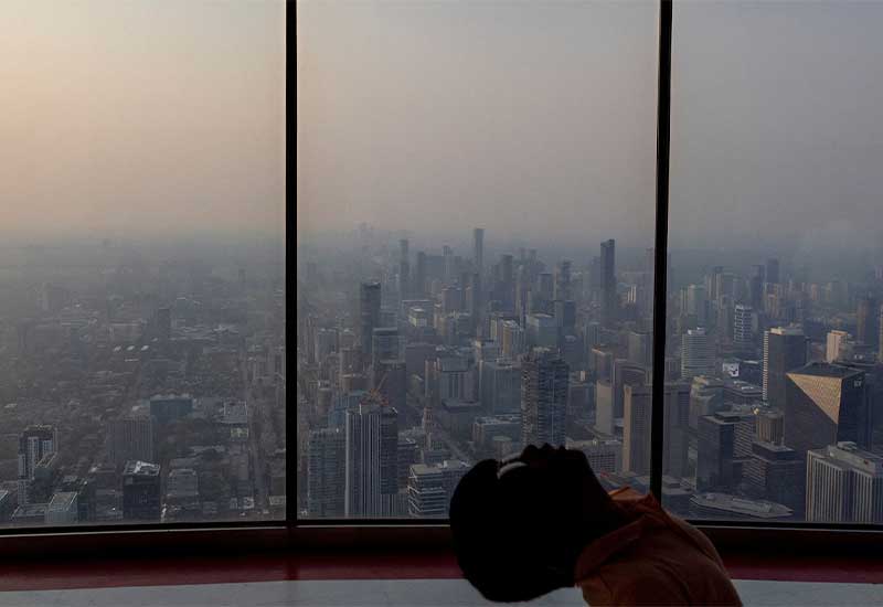 A boy leaning on the chair with foggy new york city in the backgroud