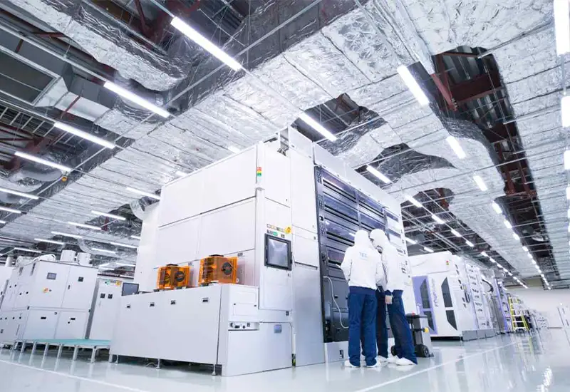 Staff working in a semiconductor cleanroom with HEPA air filtration systems on the ceiling.
